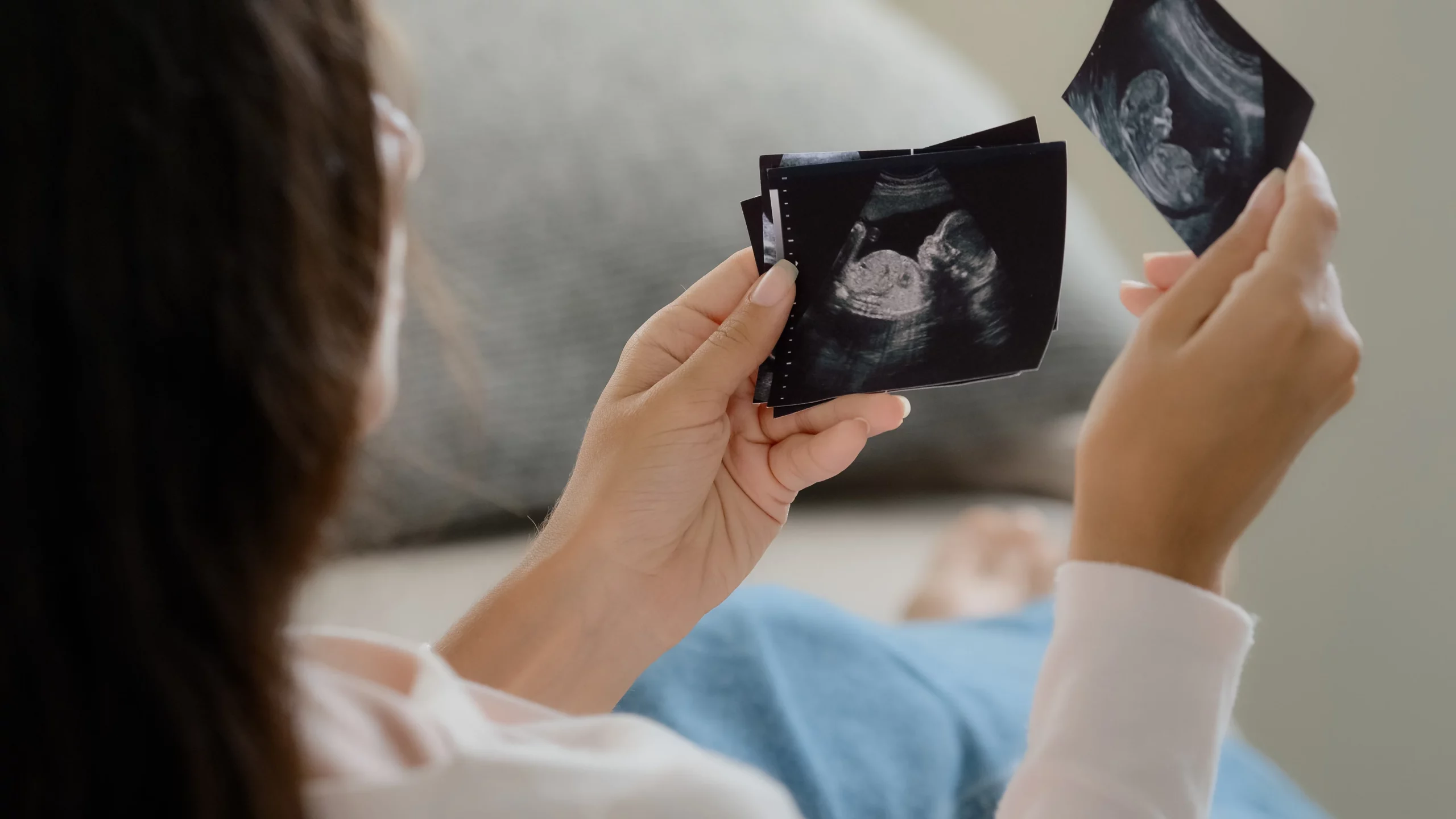 a pregnant woman of childbearing age, looking at ultrasounds, worried about the health and safety risk at work.