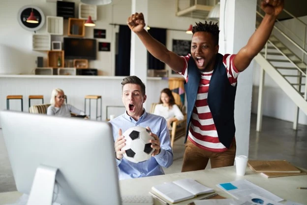 Group of employees interested in a sports event, watching football tournaments in the office without public liability. 