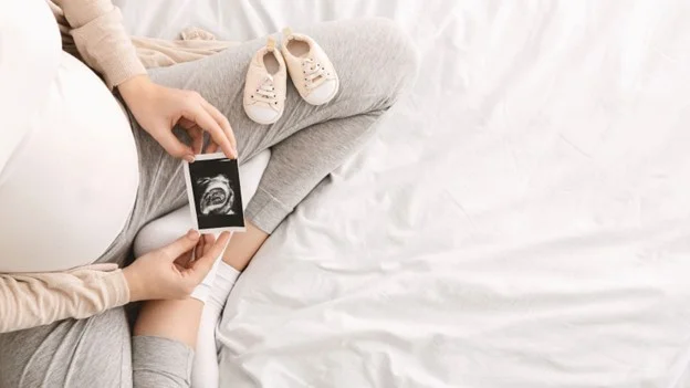 a pregnant employee looks at the scan of her baby whilst on contractual maternity leave.