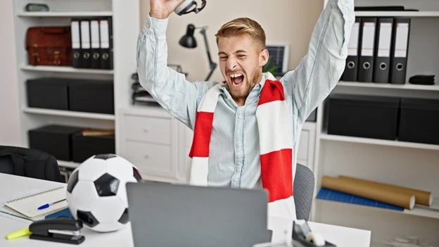 Male worker offers support to his team and participants of a sport tournament. 