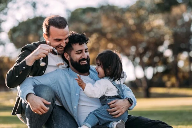 A male gay couple share the caring of their daughter, making them eligible for shared parental leave. 