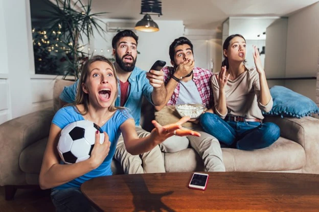 Employees watching a sports events policy at home giving support to their team avoiding employers liability insurance