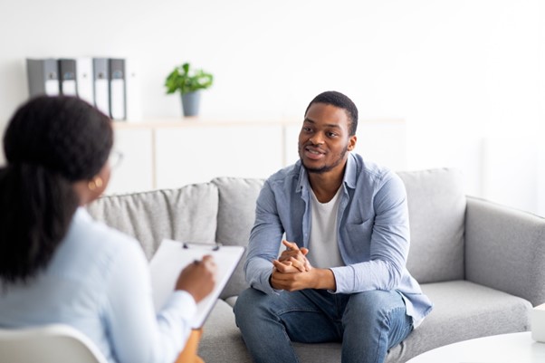 Man sat on a couch talking to a mental health counselor.