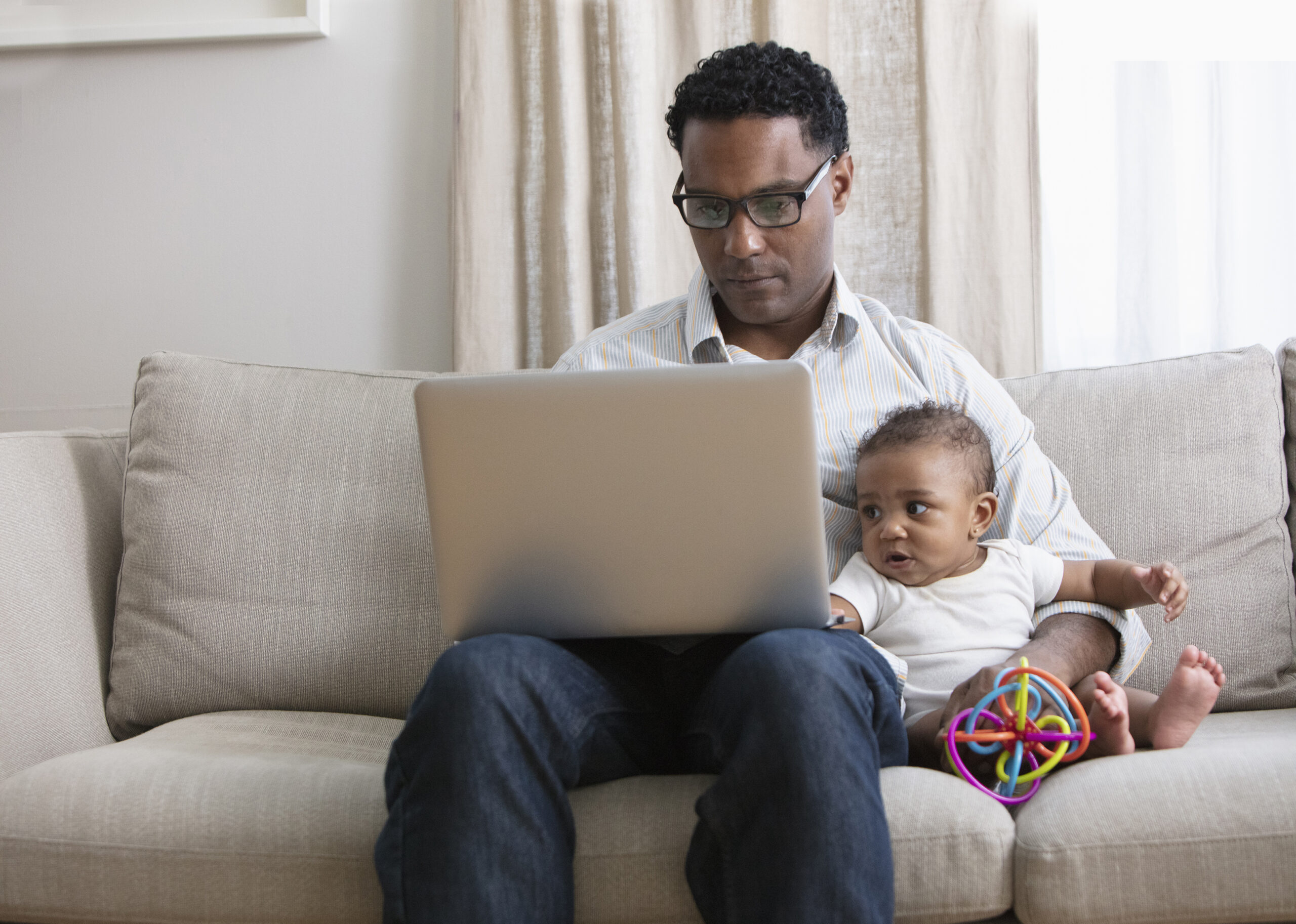 A father sat with their child while on a laptop 
